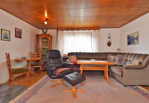 Wohnzimmer mit Couch, Sessel und TV