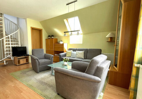 Wohnzimmer mit Couch, Sesseln und TV