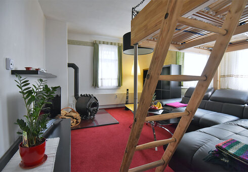 Wohnzimmer mit Couch, Ofen und TV