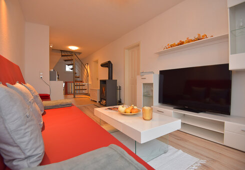 Wohnzimmer mit Couch, Kamin und TV