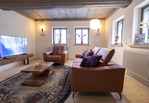 Wohnzimmer mit Couch, Sessel und TV