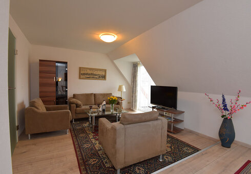 Wohnzimmer mit Couch, Sessel und TV