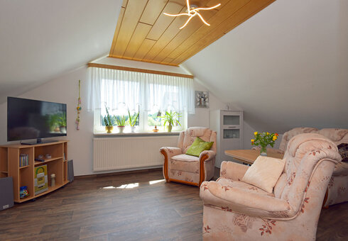 Wohnzimmer mit Couch, Sesseln und TV