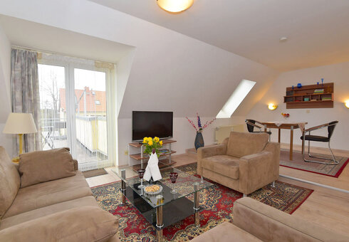 Wohnzimmer mit Couch, Sessel und TV