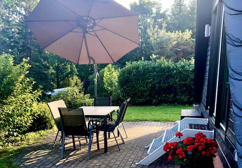 Terrasse mit Gartenmöbeln, Sonnenschirm, Grill und Feuerschale